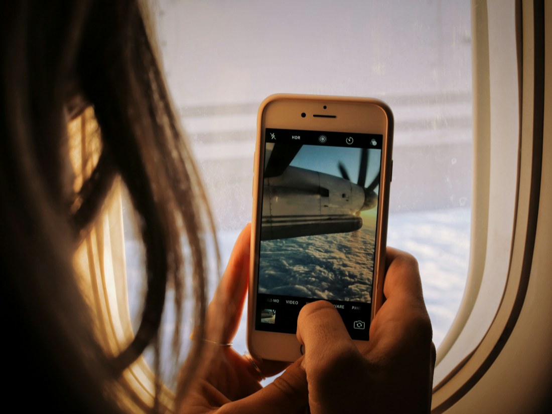 A traveler holds a phone beside an aircraft window